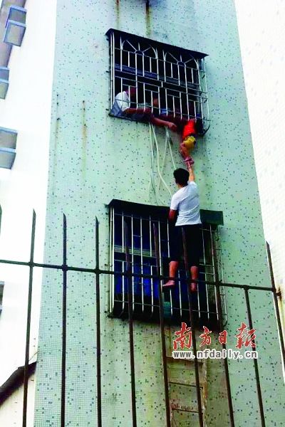 3岁的小可不慎失足，被卡在防盗网中间。住在对面5楼的欧先生上演了“托举哥”的义举。南方日报记者胡国球摄