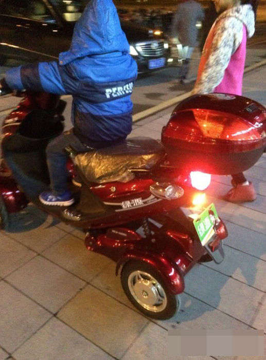 “土豪”小男孩正骑着电动车，旁边站着“女友”(网图)