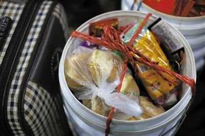 周雅丽的桶里装满了食物,她和丈夫带了一斤蛋糕、6盒方便面、一袋香肠。