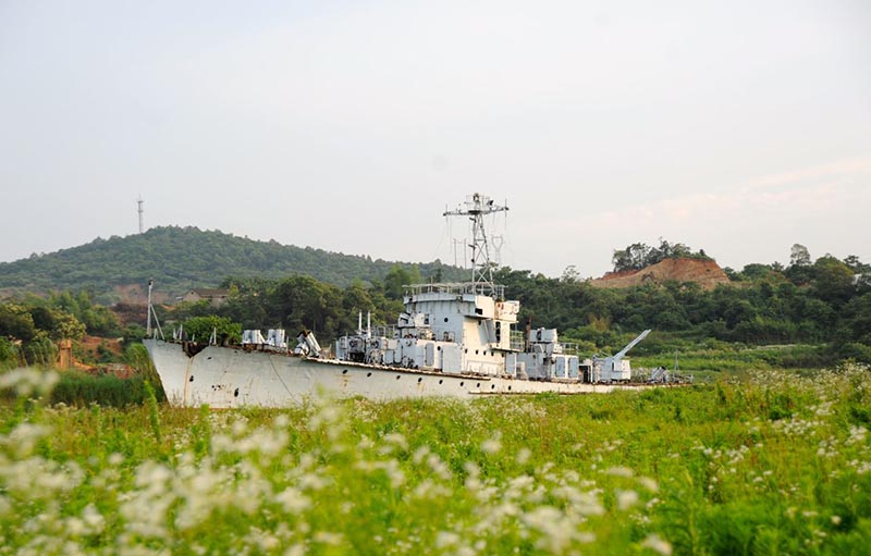     “邓小平南巡座舰”原名“宁明号”，系037型猎潜艇，1979年7月于广州黄埔港建造，耗资5000多万元。“宁明号”舰长59米，高22米，宽7.8米，重300多吨。“宁明号”为我国20世纪80年代初最先进、最精良的战舰，2005年1月正式退役。它曾被称为“英雄之舰”、“光荣之舰”和“红色之舰”。

    1984年1月26日，小平同志乘坐“宁明号”从深圳前往珠海视察。该舰在1988年的对越自卫反击战中，协同其他军舰，共击退四艘、击沉二艘越南炮舰。1990年，该舰赴南沙执行重大任务5个月；1993年到2003年，该舰多次完成了军事演习、海上巡逻、护渔护舰、抢险救灾任务。

    2005年1月11日，南海舰队将已退役的“宁明号”作为湖南爱国主义教育和国防教育基地的重要实物落户湖南湘潭，捐给湖南省湘潭市和湘潭县人民政府，并改名为“小平南巡座舰”。
    
    时至今日，该舰因经费不足而被弃置在湖南湘潭市湘江边的白沙洲上，舰身外表已锈迹斑斑，人为破坏较为严重。    摄影：童声杨