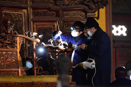 　工作人员使用软毛刷和吸尘器对太和殿的金漆雕龙宝座除尘，摄于2014年1月6日。