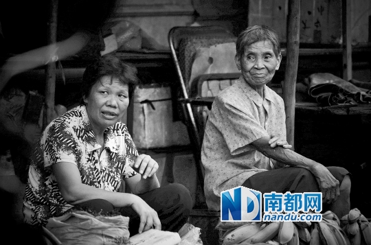 →古港的集市上，两个摊贩侧耳听旁边的故事。古港周围经常人来人往，作者说它的氛围有别于商场超市的喧闹，是可以让人停下来思考一下的。