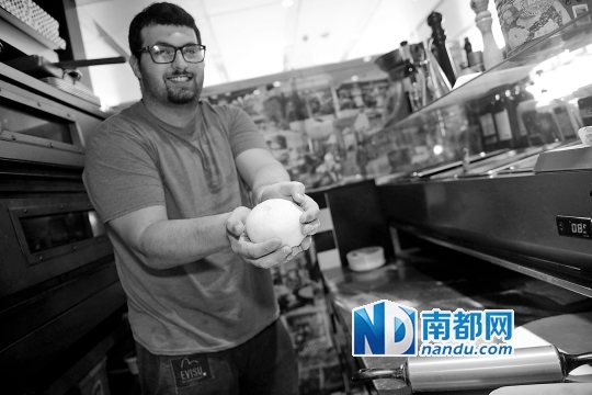 Alex在用发酵好的面团制作比萨饼底。