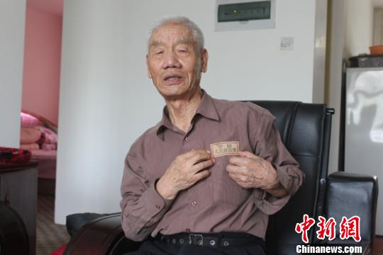 图为张万俊老人向记者展示解放军胸标的佩戴方法。　李江帆　摄