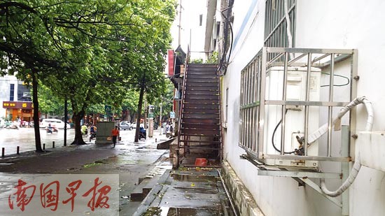 在南宁古城路，一台空调室外机距地面仅1米左右，对着人行道吹着热风。