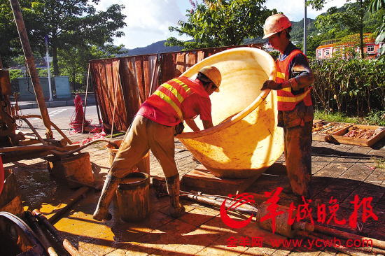 烈日下,地质勘探钻工正在往钻机旁的桶里倒入泥浆