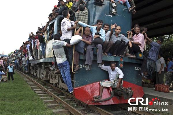 　　当地时间2014年7月27日，孟加拉国达卡，穆斯林爬上拥挤的火车，准备回家过开斋节，人潮爆满，火车里外上下都是人。图片来源：AM Ahad/东方IC