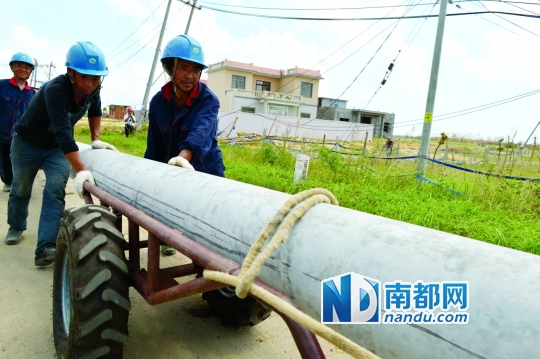 7月23日，海南昌洒镇10千伏市区线路段，工人正在运送水泥杆，抢修复电。