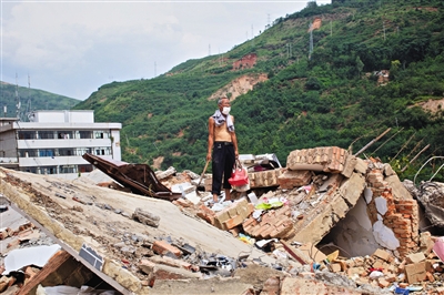 8月9日，龙头山镇，一位老者在自家房屋废墟上寻找家当。新京报记者周岗峰摄