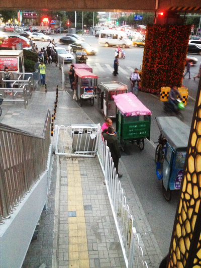 在地铁外的通道口，下班晚高峰时，“黑三轮”排队载客。人民网 沈宇波 摄