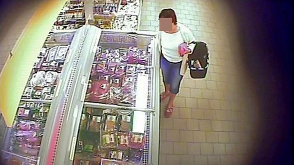 超市的监控摄像头记录了该女子的作案过程，此时她正站在冰柜旁边。