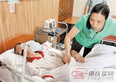 昨日，重医附一院，护工正在照顾病床上的龙启明。重庆晨报记者 甘侠义 摄