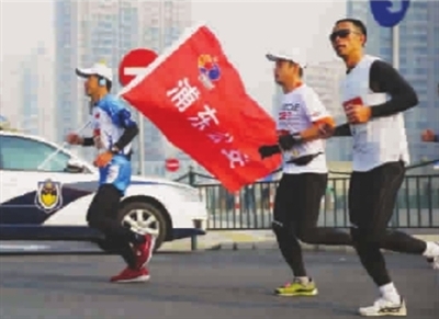 去年,倪东华(左)扛着公安的旗帜跑完全程 本版图片 tp