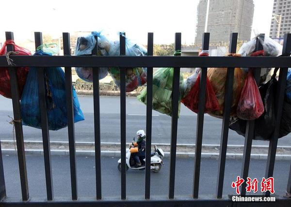 2014年12月5日，郑州市航海路一小区的围墙栅栏上，挂满垃圾袋，据居民讲，这些垃圾袋是居民们自发悬挂的，为的是引起有关部门重视，尽快处理院子里到处都是的建筑垃圾。图片来源：CFP视觉中国