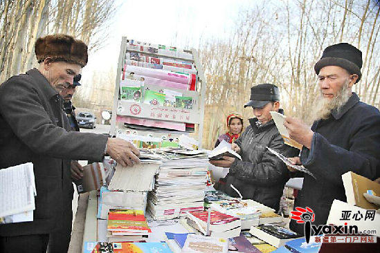 亚科瑞克乡托库扎克村村民围着亚森·卡德尔(左一)的“流动书屋”,找自己需要的书看。李彩霞 摄