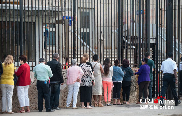 当地时间2014年12月22日，古巴民众在美国驻古巴首都哈瓦那办事处外排队等待申请签证。图片来源：CFP