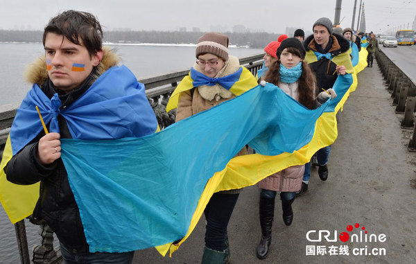 当地时间2015年1月22日,乌克兰基辅,民众身披乌克兰国旗,纪念东西乌克兰统一96周年。图片来源:GENYA SAVILOV/CFP