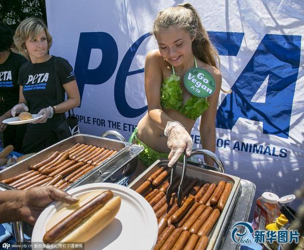 当地时间2015年7月23日,美国华盛顿,“善待动物”组织活动家身着“蔬菜比基尼”在国会山向游客分发素食热狗。图片来源:CFP