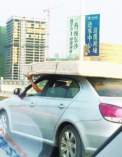 武汉司机左手扶床右手开车 轿车顶着床垫跑(图)
