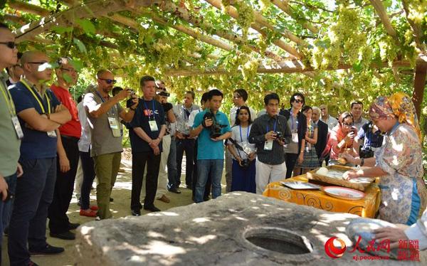 在葡萄沟布依鲁克村,代表们走进普通维吾尔族家庭看打馕。陈维华 徐蒙 摄