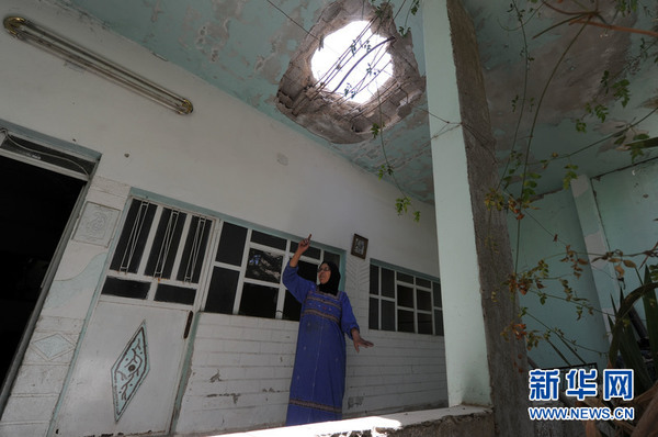 在叙利亚大马士革农村省哈塞尼亚镇，一名女子站在自家被炸屋顶下面。新华社记者 张迺杰摄