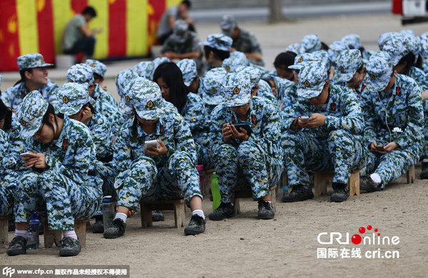 2015年8月25日,北京大学2015年学生军训团进行消防演练及体验活动,参加活动开幕式的北大新生萌妹子低头玩手机的随处可见。图片来源:CFP