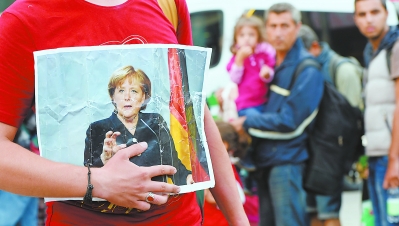 5日，在德国南部慕尼黑，一名难民在抵达火车站时手持德国总理默克尔的照片。