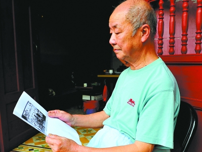 杨国铭拿着父亲的旧照，回忆“卢部”浴血淞沪会战的往事。