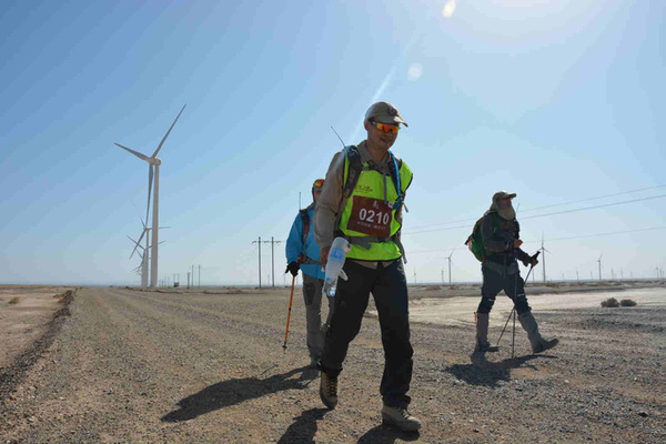 三名戈友大步向前,把高大的风车甩在背后