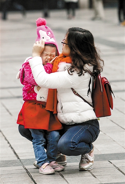 解放碑步行街，妈妈给孩子戴上御寒的帽子。 本报记者 高科 摄