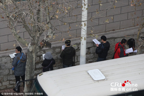 　　2015年11月29日，山东省烟台市，考生在南通路小学考点门前临阵复习。图片作者:凤尾竹/视觉中国