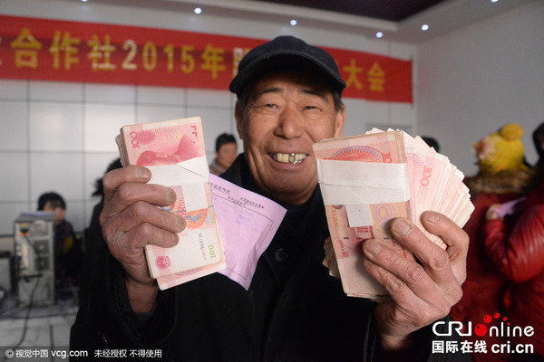 2015年12月19日，在河北保定市望都县恒业合作社举行的2015年股金分红大会上，不少农民拿到分红后高兴地合不拢嘴。图片来源：陈卫红马立方/视觉中国