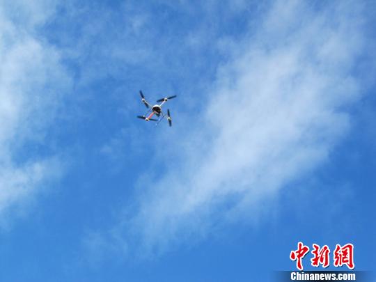 图为无人机在空中搭载便携式检测设备，进行大气污染跟踪监测实验。