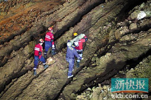 ■救援人员抬着设备在泥泞中前行。