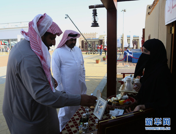 传统民俗市场上，一位当地女商户（右）在向两位参观者兜售自制香水。新华社记者 安江 摄