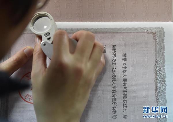 北京住房公积金管理中心的工作人员在查验一本房屋所有权证的真伪（1月20日摄）。新华社记者 罗晓光摄