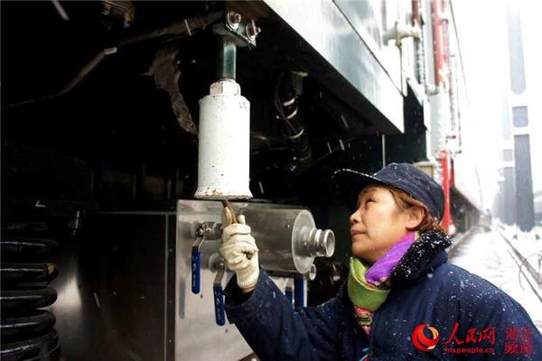 武汉铁路局武昌客车车辆段女职工冒雪检查列车设备质量。（方昉 摄）