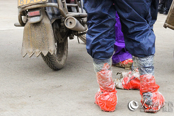 为了应对一路上的雨雪天气，摩骑大军雨衣、塑料袋、胶带齐上阵（陆高宝/摄）