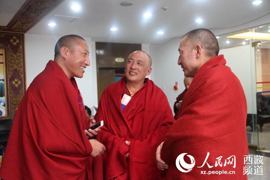 3位西藏宗教界政协委员聚在一起讨论会议报告。吴雨仁 摄