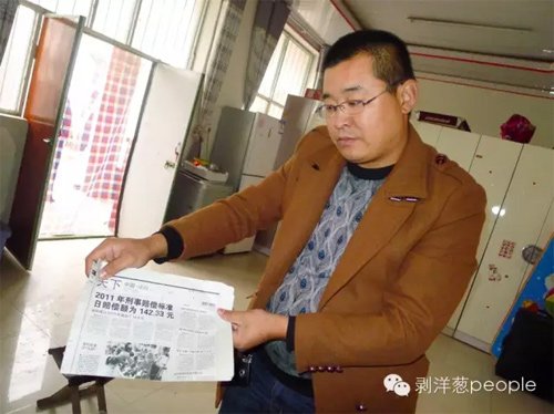 李俊卜展示在狱中带出来的报纸，上面有关于国家赔偿的消息。