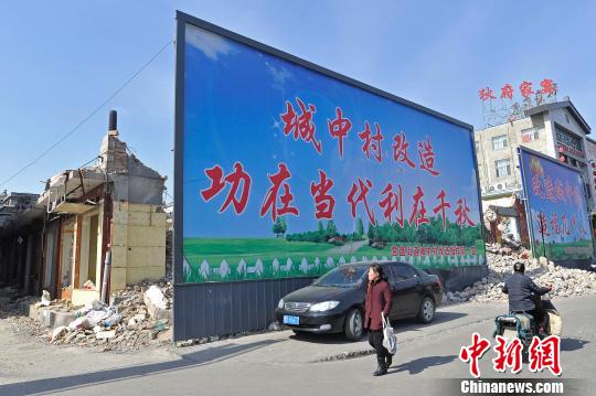 2月29日，山西太原，民众从巨幅城中村改造动员海报前走过。韦亮　摄