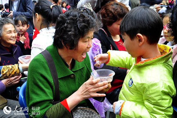 “拗九节”公益活动现场,小朋友们纷纷为老人喂食“拗九粥”。 吴隆重 摄