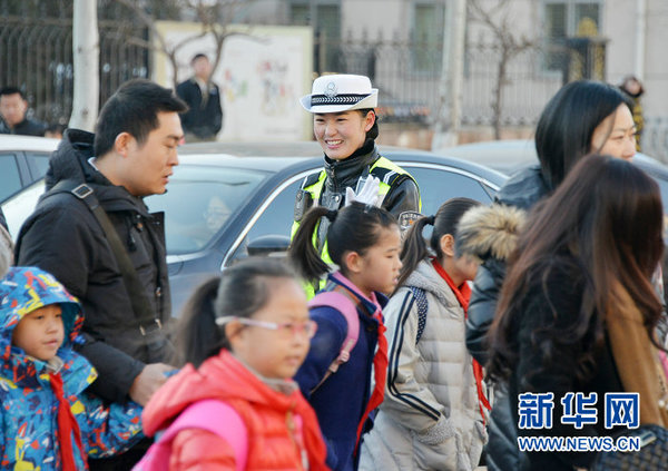 3月10日清晨,包头市女交警王倩颖在校园门口执勤(新华社记者王靖 摄)