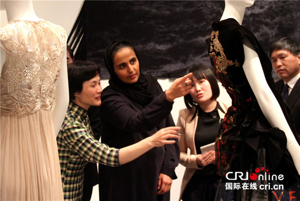 卡塔尔博物馆管理局主席玛娅萨公主仔细观看一件现代服饰上的丝绸图案