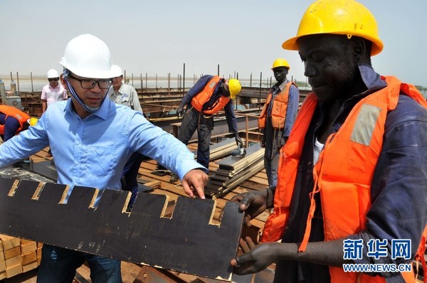 萨瓦金牲畜码头工地，项目经理程飞（前左）在指导当地工人施工。新华网记者李紫恒摄