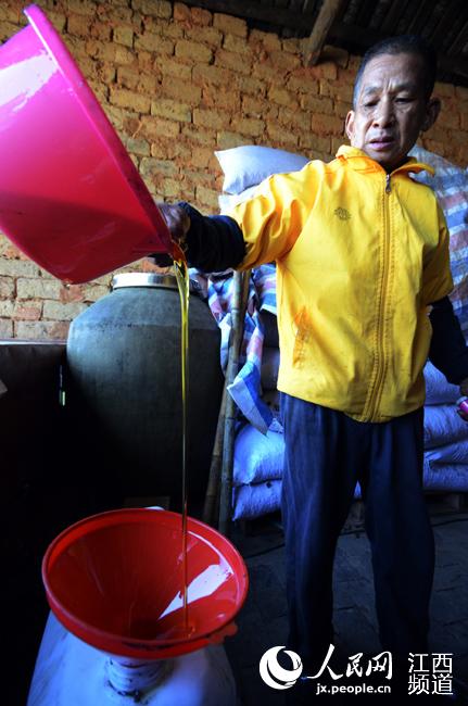 榨油师傅将飘香的山茶油装桶售卖。