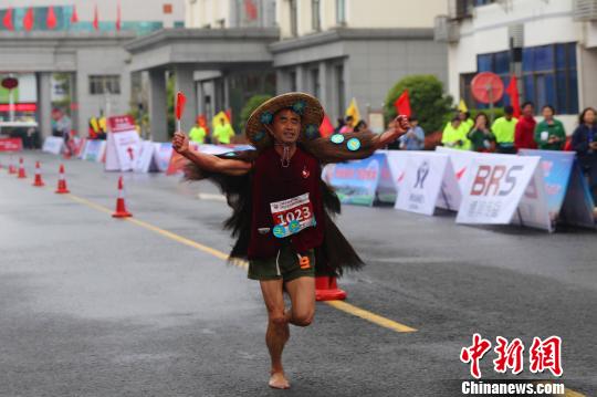 马拉松比赛现“赤脚蓑衣哥” 李重庆 摄