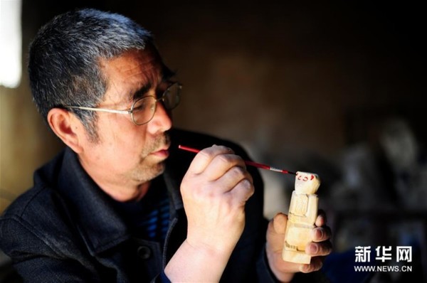 　　 4月13日，在河南省方城县独树镇砚山铺村，方城石猴代表性传承人王国庆在给石猴上色。