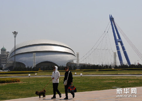 4月18日，两名行人从星海广场东南侧的大连贝壳博物馆前经过。新华网图片 吕文正 摄