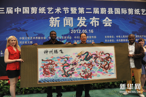 5月16日，对外经济贸易大学国际学院的留学生在新闻发布会上展示他们和剪纸大师共同创造的剪纸作品。新华网图片 刘长龙 摄